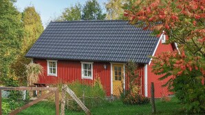 A red house with a dark tiled roof, white windows, and a yellow door. - Cozy home in Tyringe with WiFi (Tyringe)