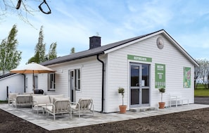 A white building with a reception desk, outdoor seating, and a sign indicating a reception and butik. - Stunning home in Ystad with WiFi (Ystad)