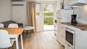 Cocina compacta con comedor, sofá y vista a través de un ventanal.