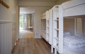 A room with bunk beds, a small table, and a view of a garden through a door. - Beautiful home in Ystad with WiFi (Ystad)
