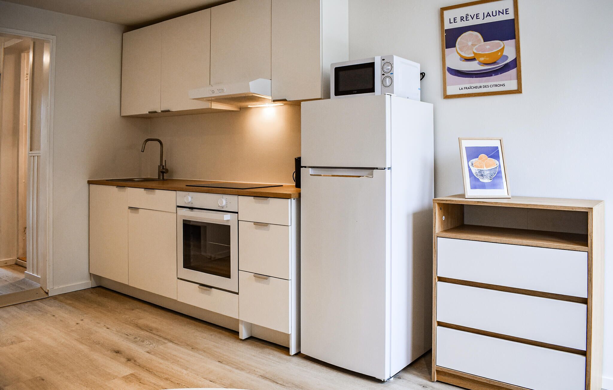 A compact kitchen with a microwave, oven, and refrigerator.