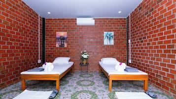 Una habitación con dos camas, una mesita con un florero y un aire acondicionado de pared.