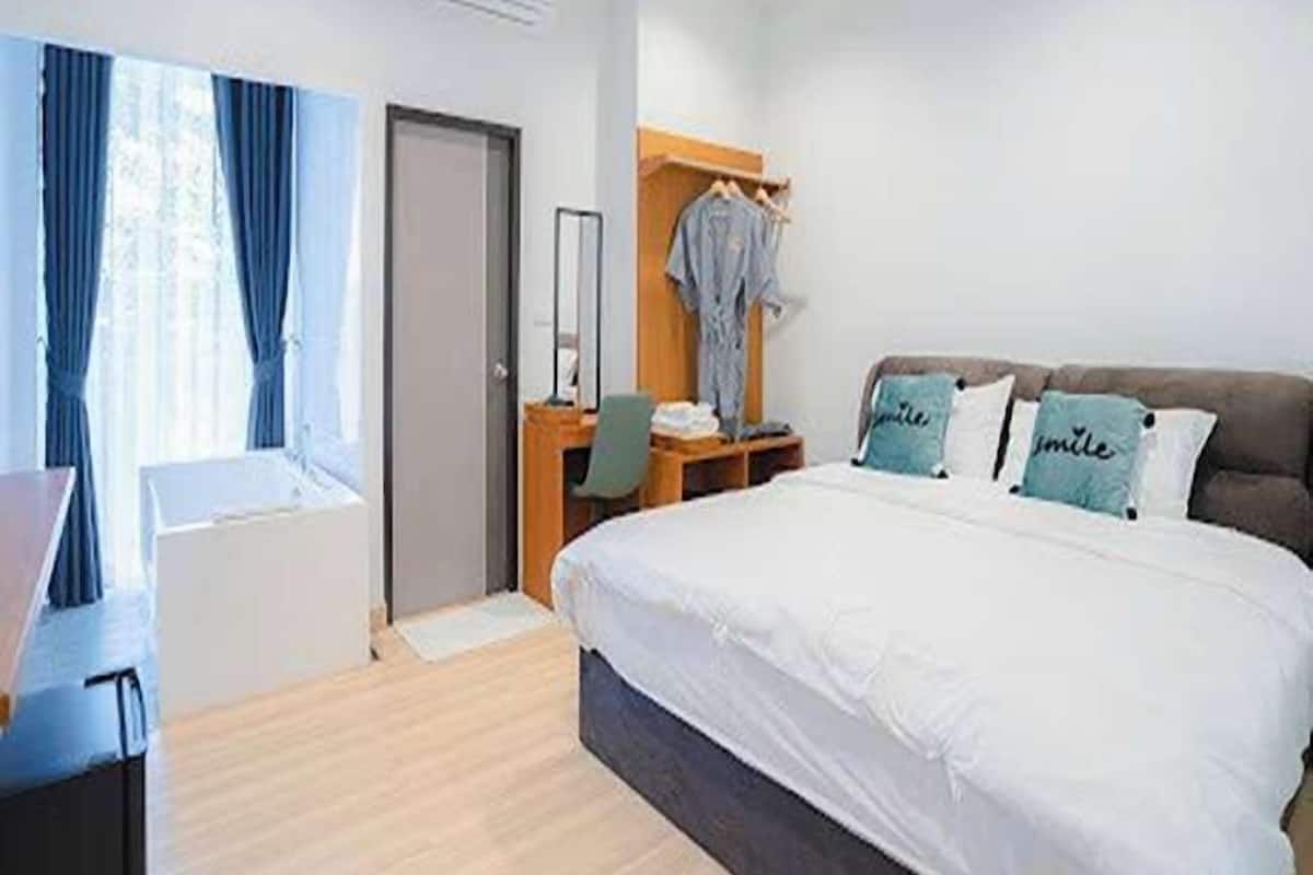 A modern hotel room with a large bed, a desk, and a wardrobe.