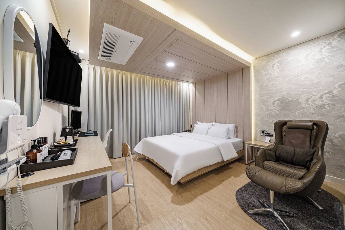Habitación de hotel moderna con cama, escritorio, teléfono, silla y televisión.