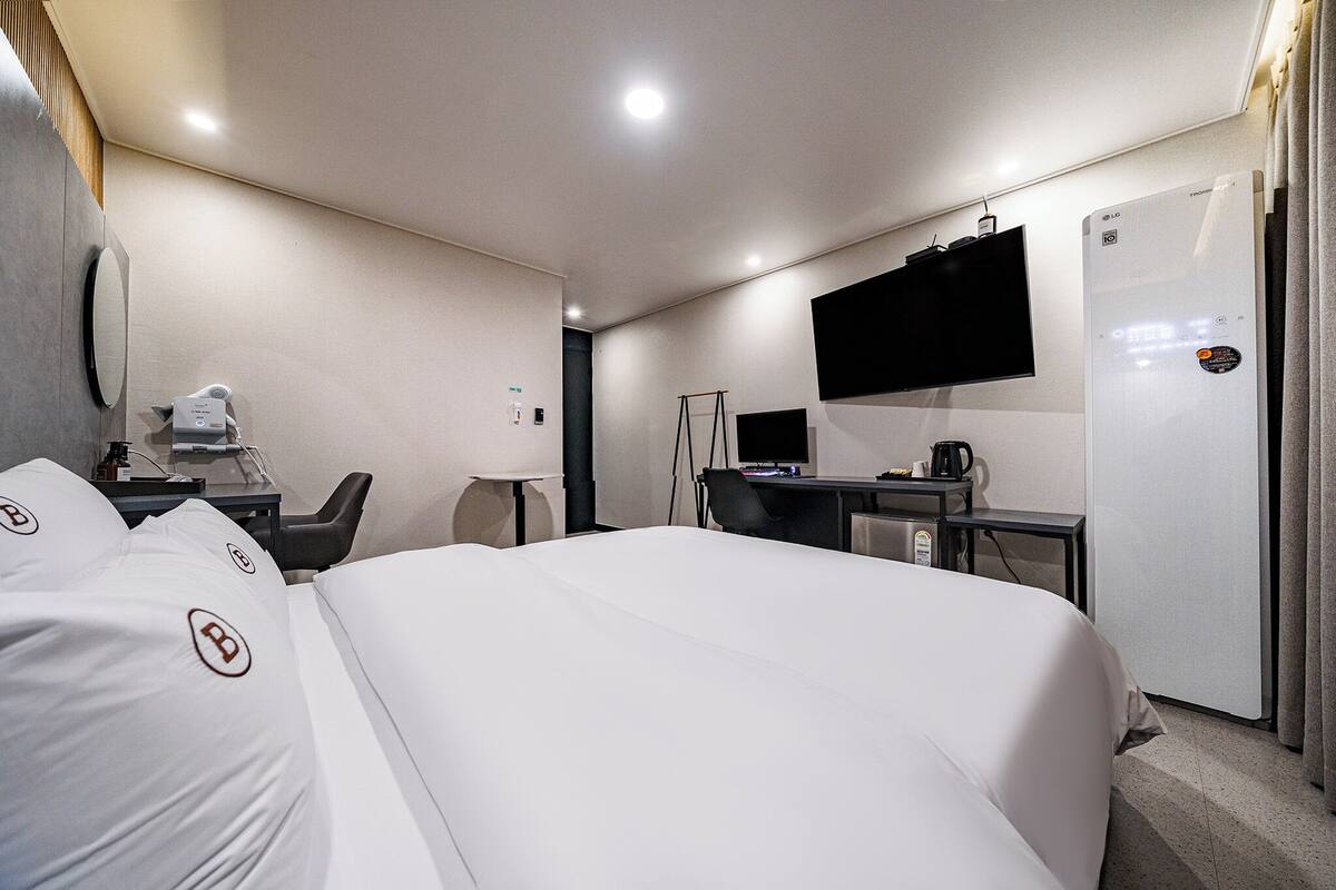 Habitación de hotel con una cama grande, escritorio con computadora, televisión de pantalla plana y minibar.