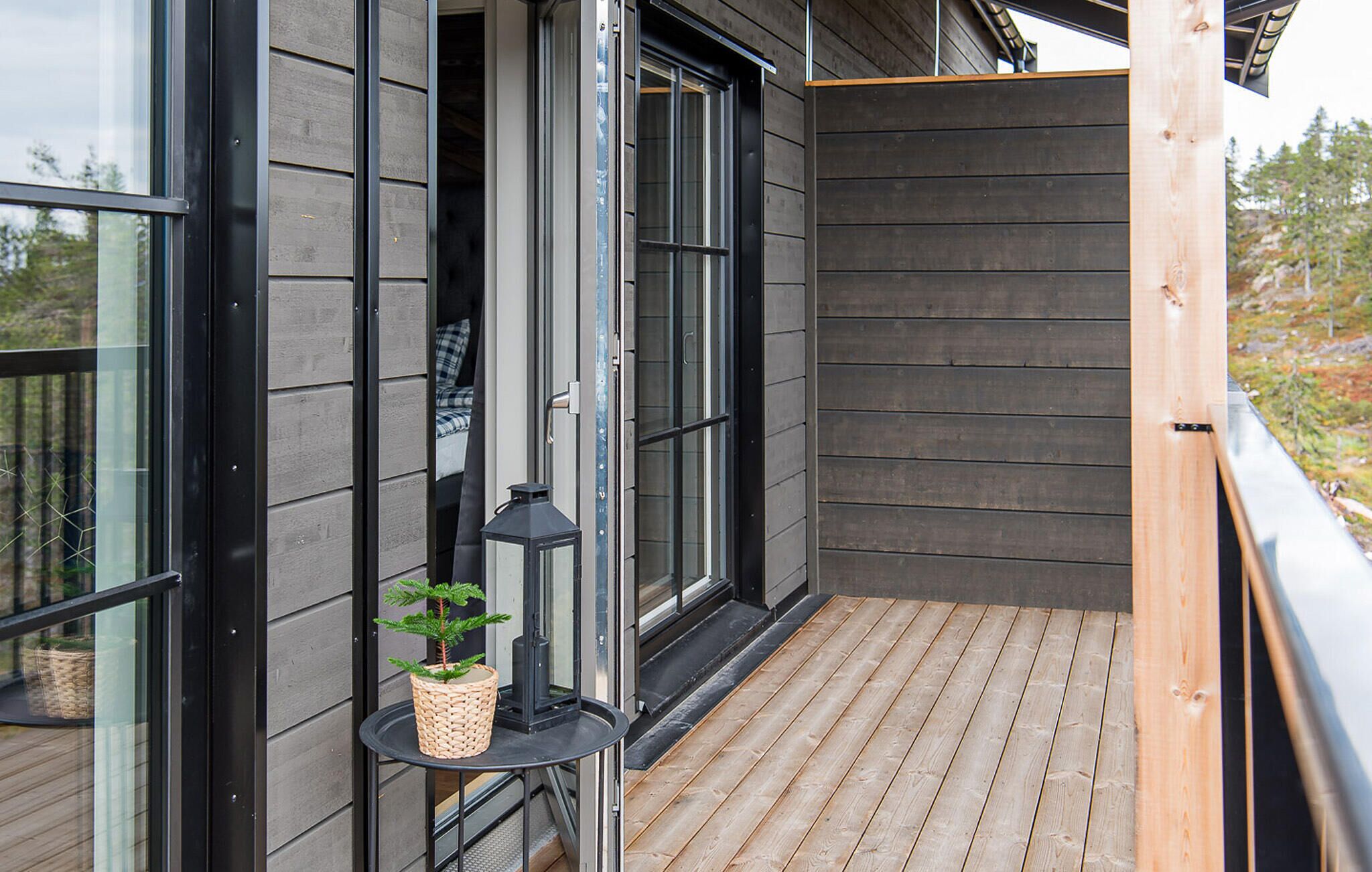 A wooden deck with a potted plant and a lantern.