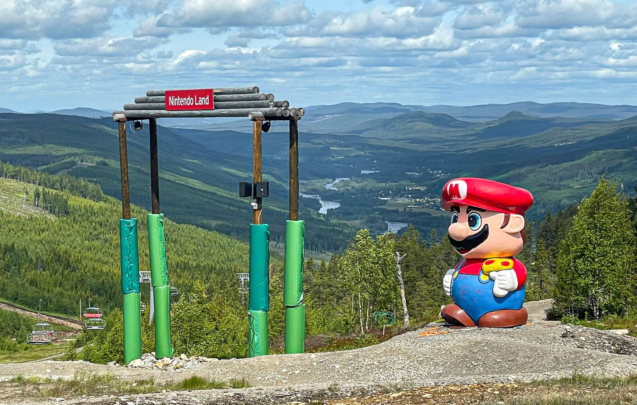 A large Mario statue at the top of a mountain with a Nintendo Land sign.
