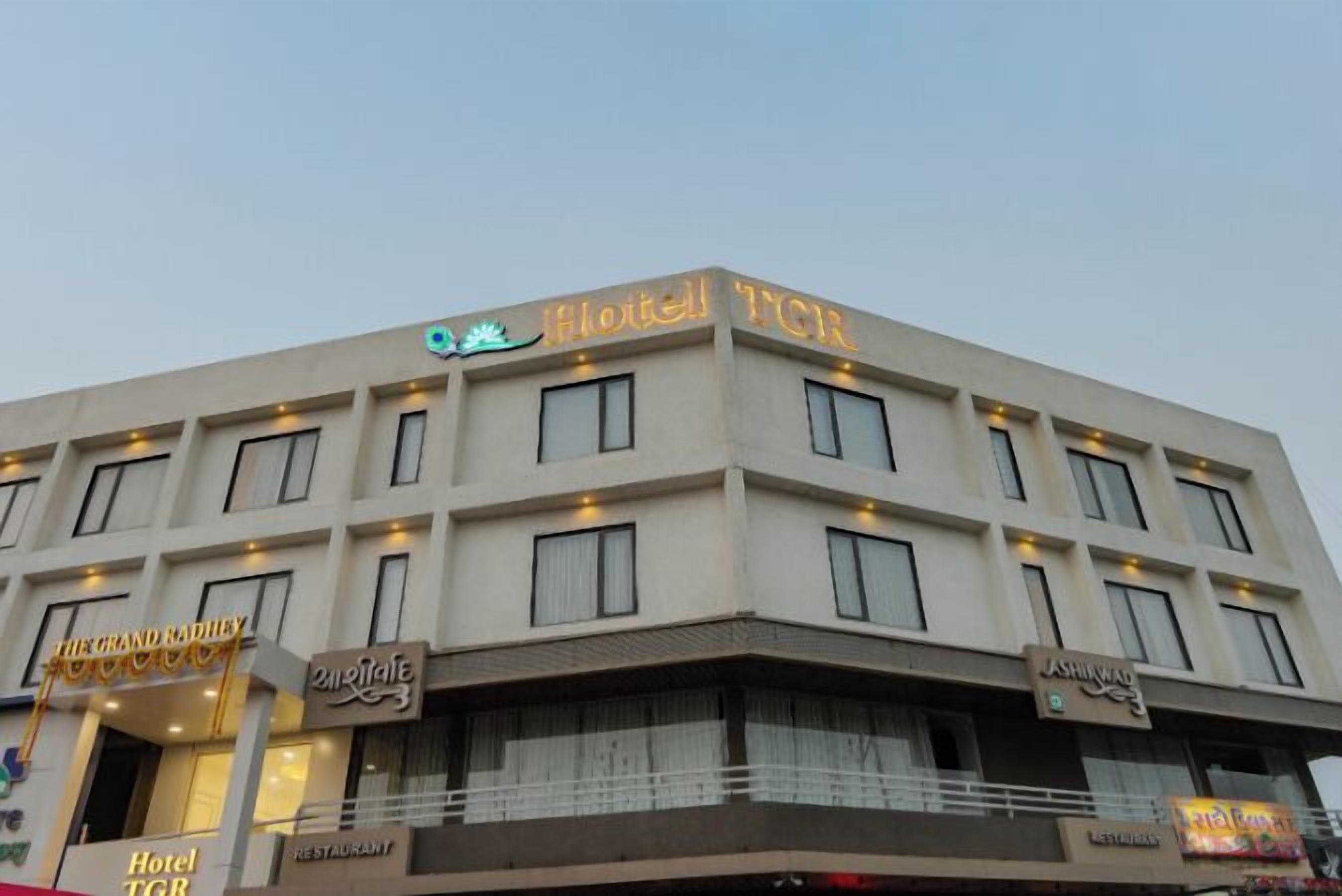A multi-story hotel with a flat facade, multiple windows, and signage for various amenities including a restaurant and a restaurant named "Ashirwad."