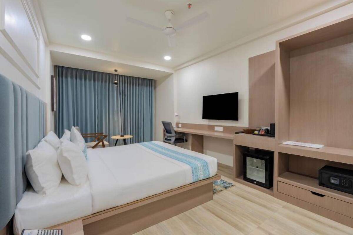 A modern hotel room with a bed, desk, and TV.