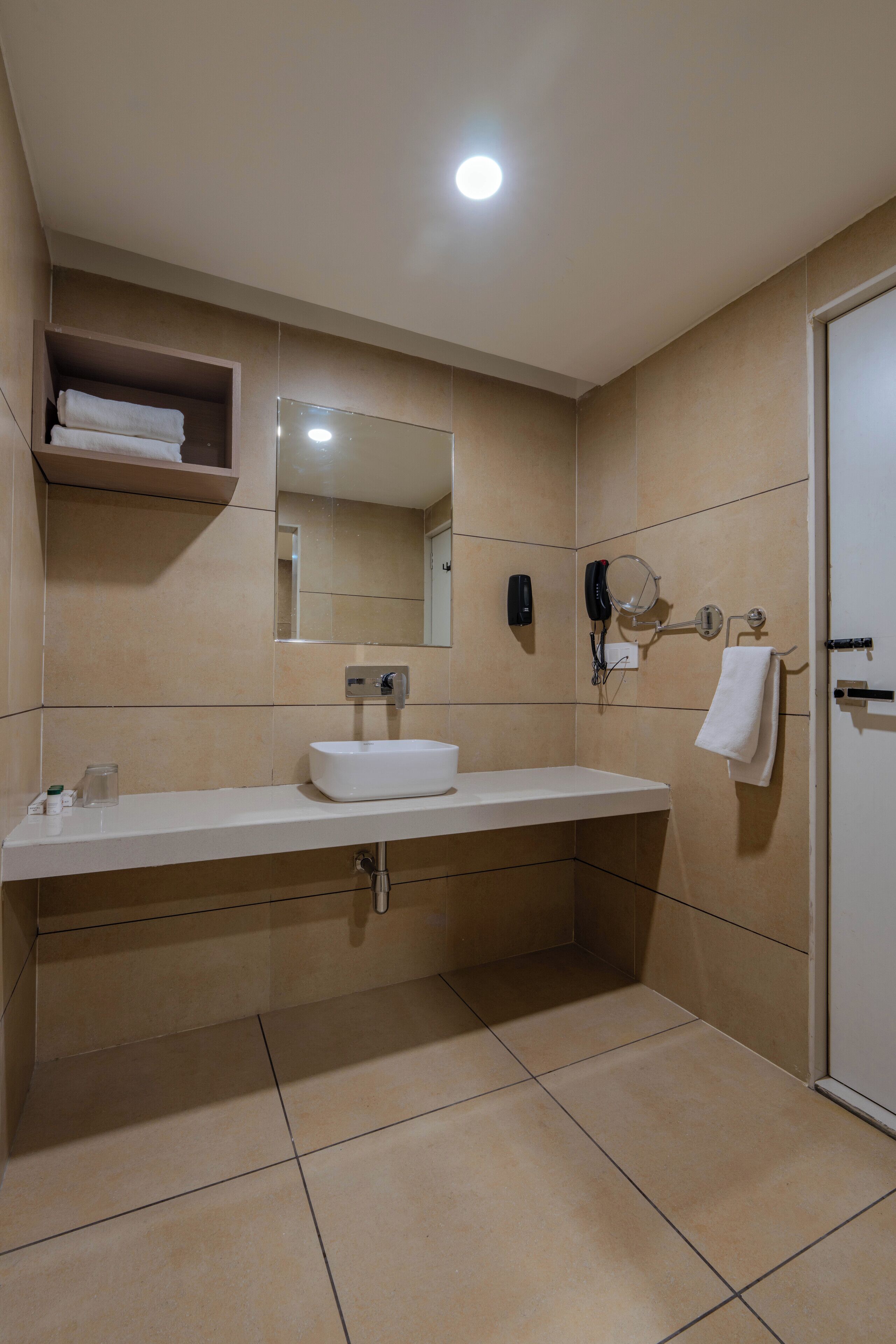 A modern bathroom with a white sink, mirror, and towel rack.