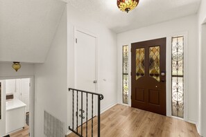 A hallway with a wooden floor, a white door, and a brown door with decorative glass panels. - 5BR San Antonio Home - Large Private Pool, Covered Patio, BBQ & Outdoor Games (San Antonio)