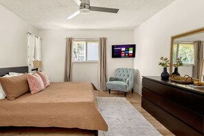 A bedroom with a bed, a chair, a dresser, a television, and a window with curtains. - 5BR San Antonio Home - Large Private Pool, Covered Patio, BBQ & Outdoor Games (San Antonio)