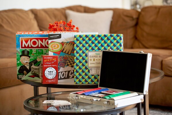Una colección de juegos de mesa sobre una mesa de vidrio, con un sofá marrón al fondo.