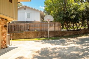 Ein Wohngebiet mit einem Basketballkorb, einem Holzzaun und einem Haus im Hintergrund.