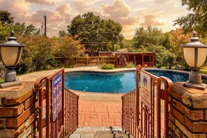 A swimming pool with a wooden fence and two lamp posts on either side. - 5BR San Antonio Home - Large Private Pool, Covered Patio, BBQ & Outdoor Games (San Antonio)