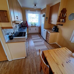 A compact kitchen with wooden cabinets, a sink, a coffee maker, and a dining area with a table and chairs. - Våxtorp family villa near Vallåsens skidbacke och cykelpark (Våxtorp)