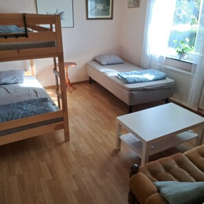 A room with a bunk bed, a single bed, a small table, and a sofa. - Våxtorp family villa near Vallåsens skidbacke och cykelpark (Våxtorp)