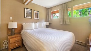 Un dormitorio con una cama, dos lámparas de noche, una mesita de noche, un aparador y dos cuadros en la pared.
