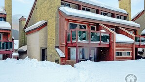Un edificio de varios pisos con fachada roja y chimeneas amarillas, rodeado de nieve.