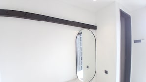 A modern, minimalistic room with a built-in bench, a large mirror, and a door leading to another space. - Cibulan Indah Hotel (Cisarua)