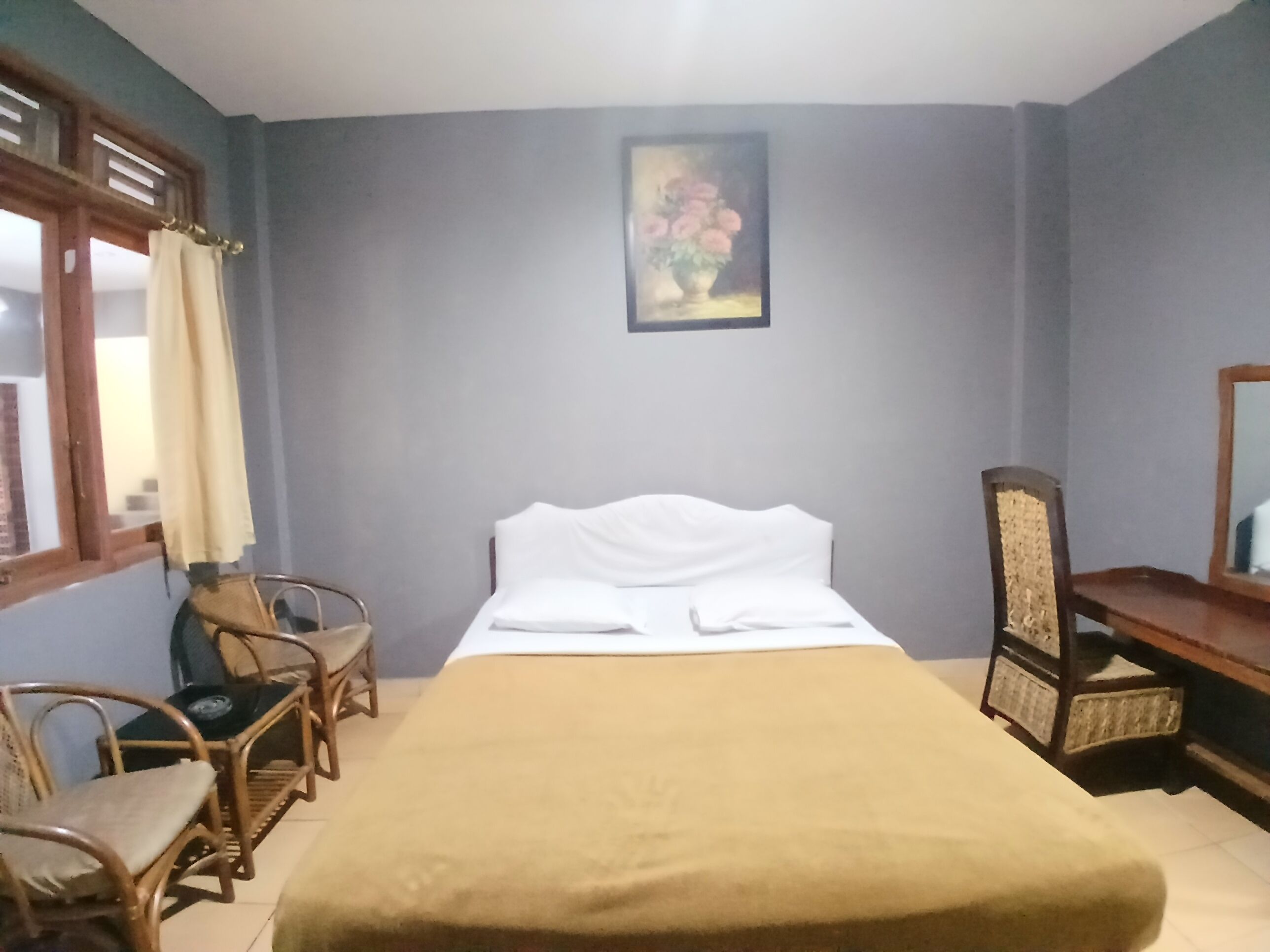 A bedroom with a bed, a chair, a desk, and a painting on the wall.