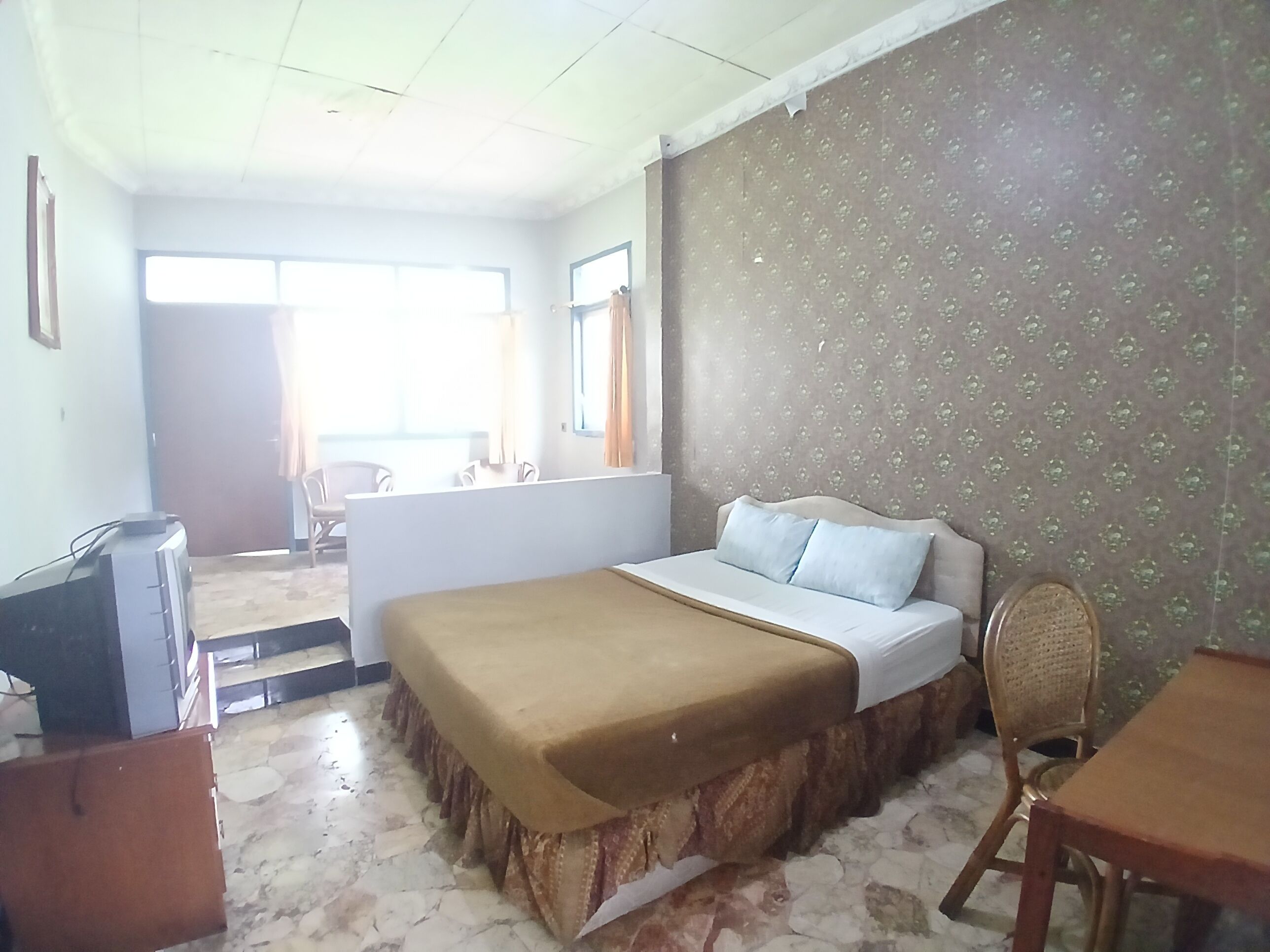 A bedroom with a bed, a desk, and a chair. There is a window and a door in the room.