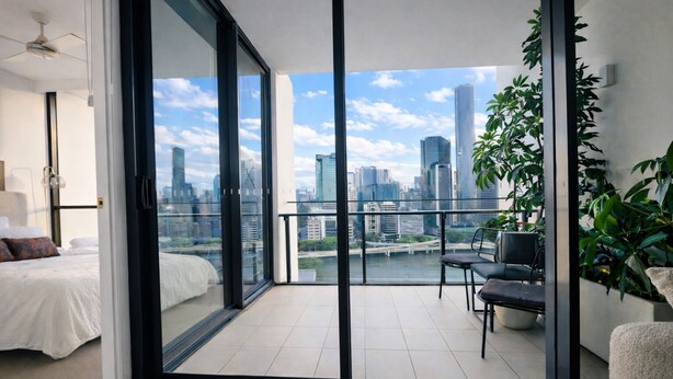 A modern bedroom with a large sliding glass door leading to a balcony with a city view. - Million Dollar Views Luxury Apartment with 3pm Late Checkout (South Brisbane)