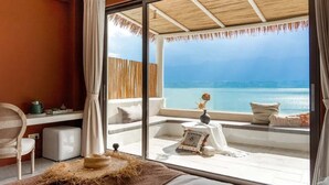 A room with a large window overlooking the sea, a wicker chair, a small table with a vase, and a cozy seating area with cushions. - Dali Pure-Soul Seaview Resort Hotel (Dali)