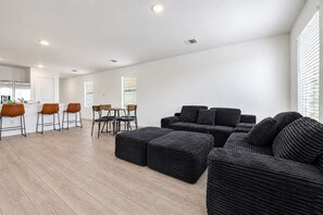 A modern living room with a sofa set, a dining area with chairs, and a kitchen visible in the background. - 3BR Near Gruene Historic District, Comal, and Guadalupe Rivers & Schlitterbahn (New Braunfels)