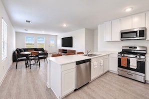 A modern kitchen with white cabinetry, a stainless steel dishwasher, a built-in oven, and a microwave. - 3BR Near Gruene Historic District, Comal, and Guadalupe Rivers & Schlitterbahn (New Braunfels)