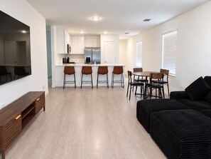 A modern kitchen with white cabinets, a central island, and bar stools. - 3BR Near Gruene Historic District, Comal, and Guadalupe Rivers & Schlitterbahn (New Braunfels)