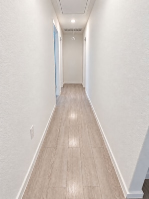 A narrow hallway with light-colored walls and wooden flooring. - 3BR Near Gruene Historic District, Comal, and Guadalupe Rivers & Schlitterbahn (New Braunfels)