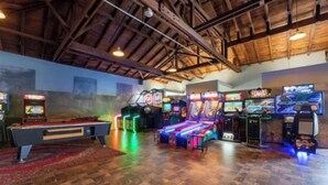 Een kamer met een pooltafel, speelautomaten en een houten plafond.