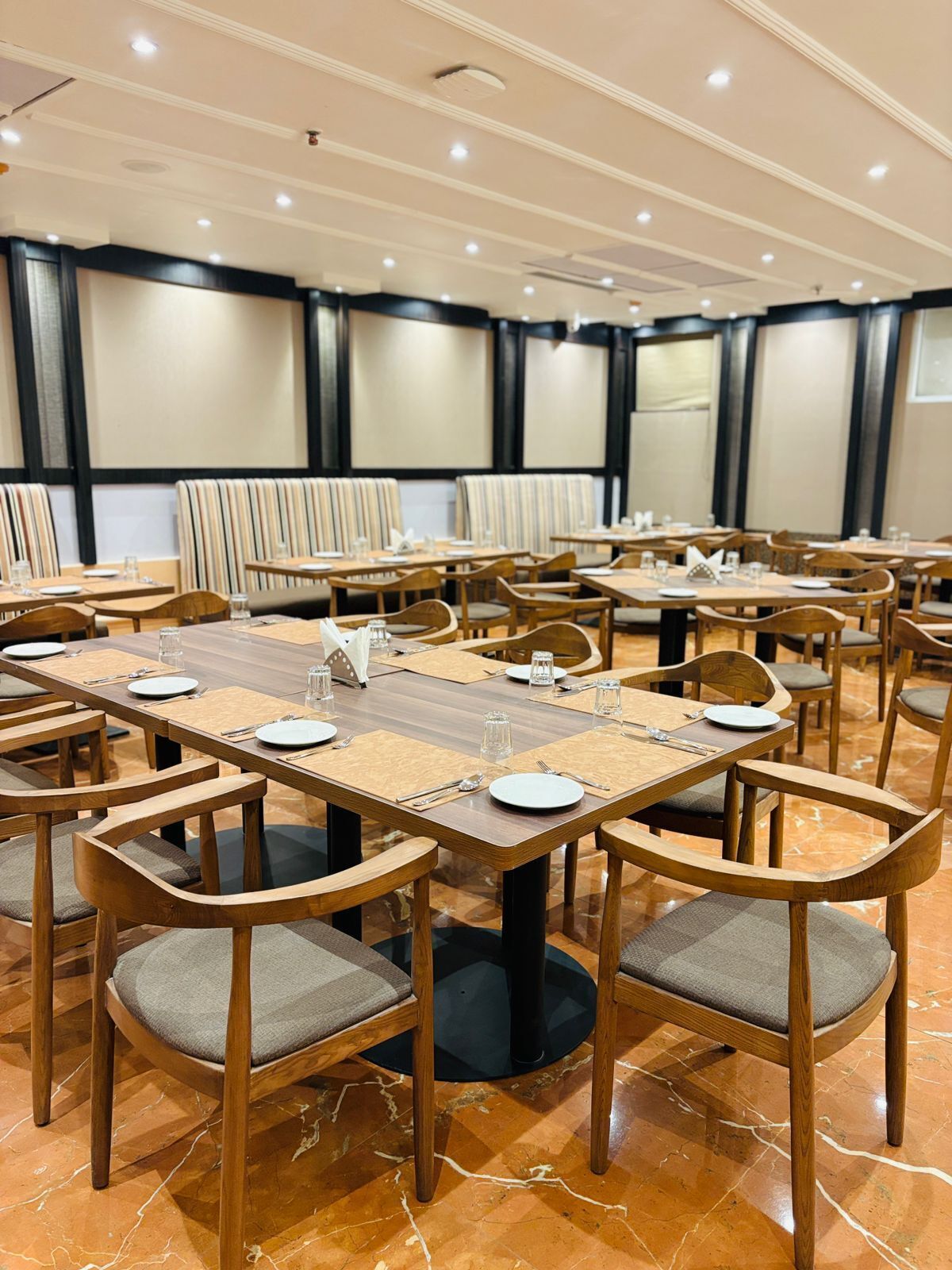 A conference room with multiple tables and chairs, equipped with nameplates, water glasses, and cutlery.