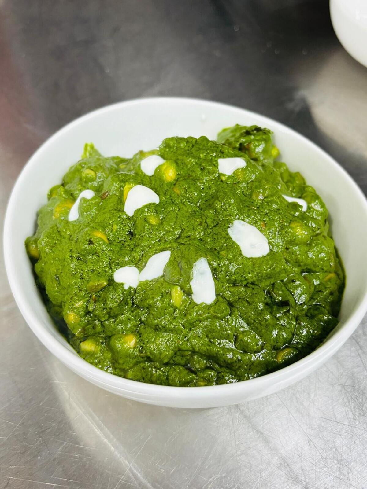 A bowl of green vegetable dish with white toppings.