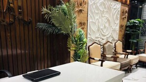 Een receptiebalie met een laptop, een houten wandpaneel en een decoratieve wand met een kandelaar.