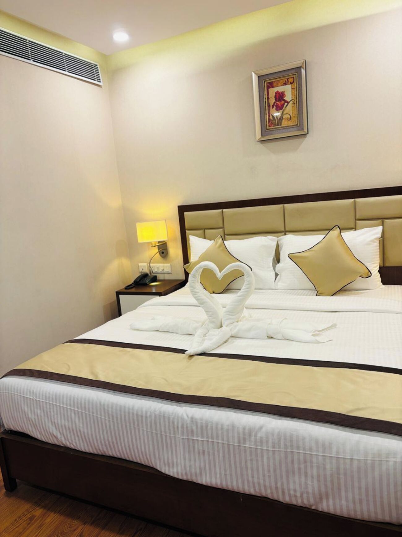 A hotel room with a bed, a nightstand, a lamp, and a framed picture on the wall.