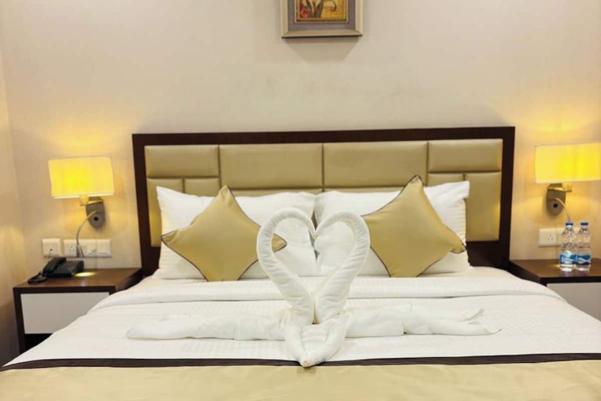 Une chambre d’hôtel avec un lit, deux tables de chevet et un tableau encadré au mur.