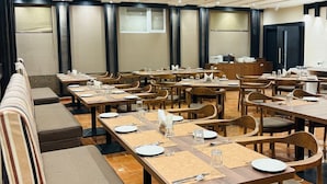 Een hotel eetruimte met meerdere tafels en zitgedeeltes, voorzien van borden, bestek en glazen.