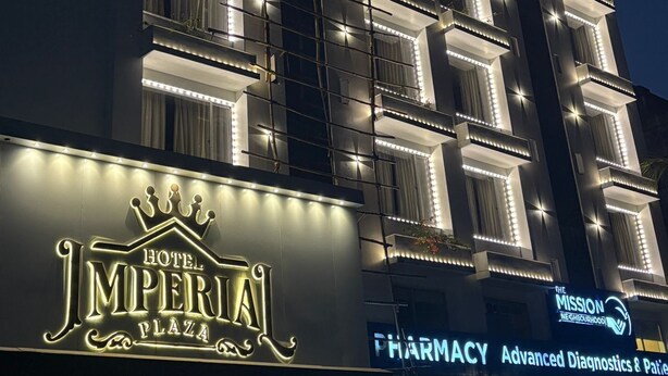 Een hotel met een opvallend bord voor 'Hotel Imperial Plaza' en een apotheek met 'Advanced Diagnostics & Patient Care' diensten.