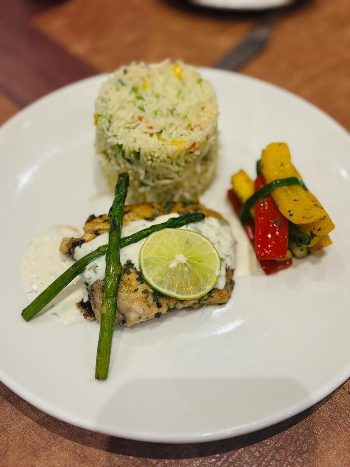Un plato de arroz, pescado a la parrilla y verduras asadas.