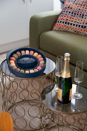 Ett glasbord med en dekorativ metallram, en flaska champagne och två glas på bordet.