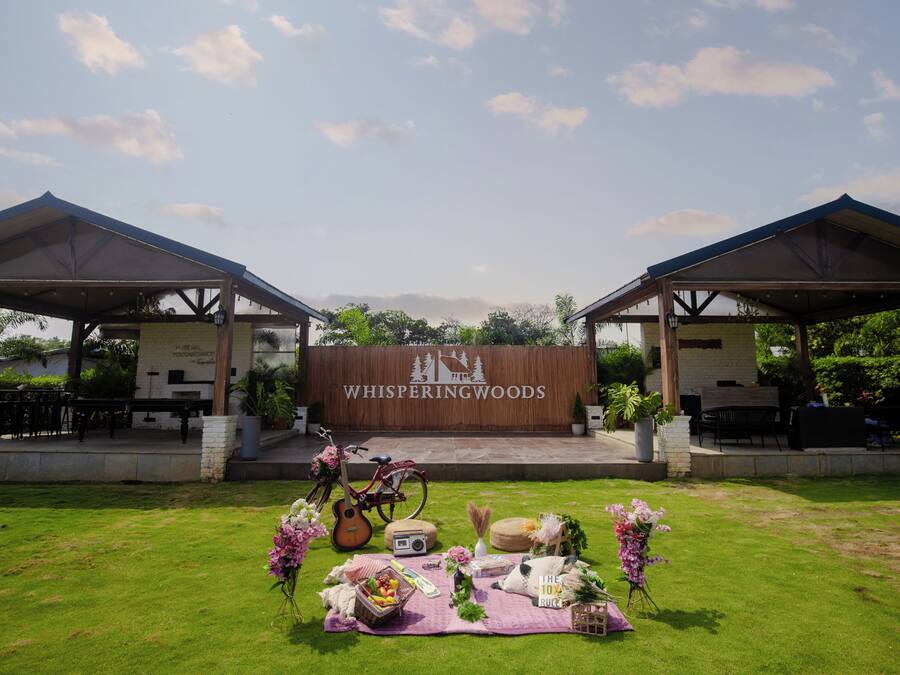 An outdoor event setup with a stage, two covered areas, and a grassy lawn.