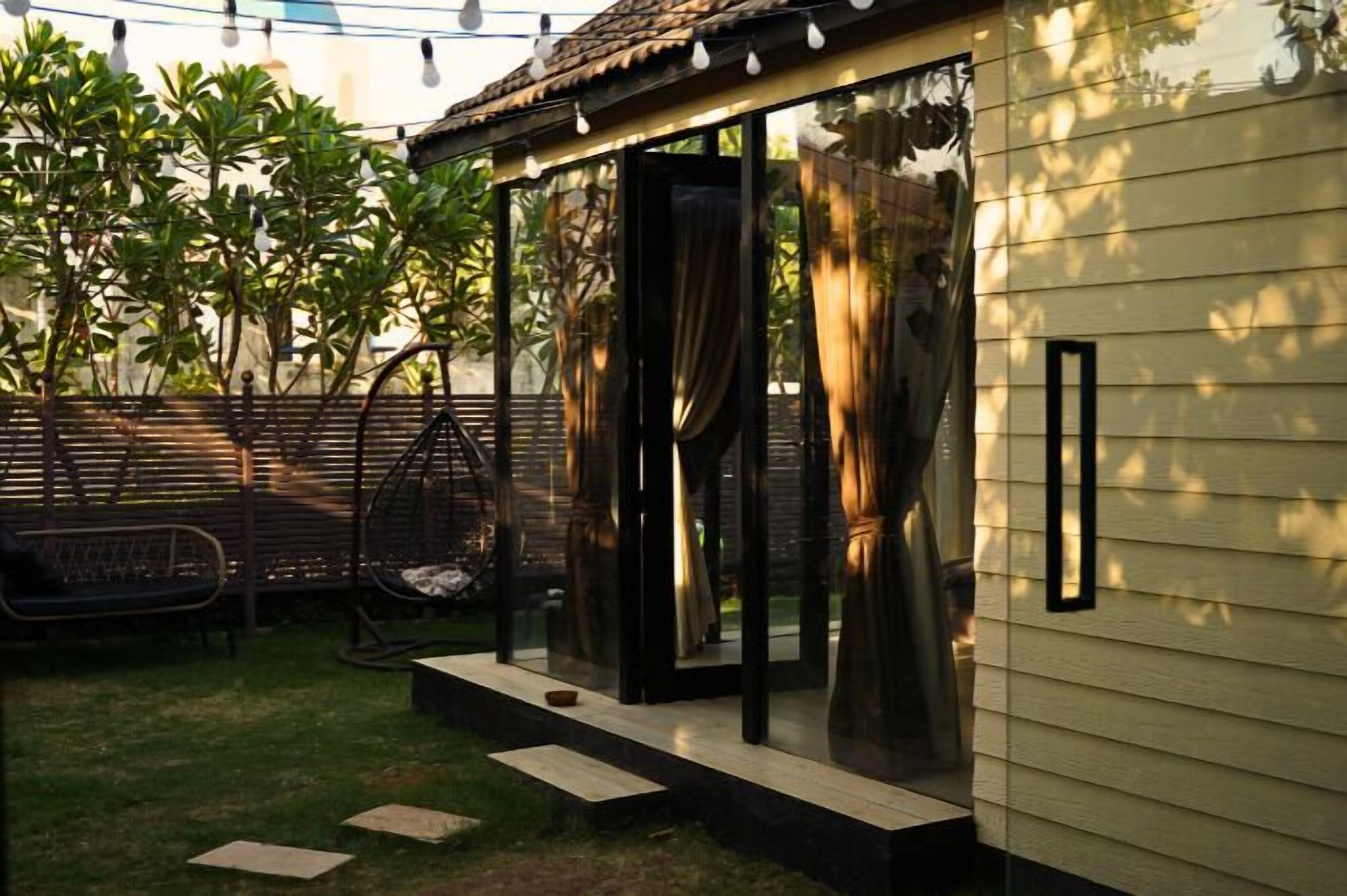 Una casa moderna con puerta de vidrio, una silla colgante y un pequeño patio.