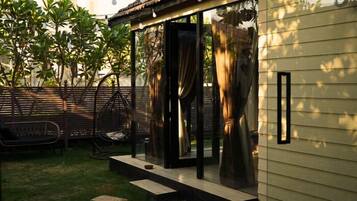 Una casa moderna con puerta de vidrio, una silla colgante y un pequeño patio.