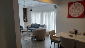 En moderne stue med sofa, lænestole, et sofabord og et spiseområde med bord og stole.