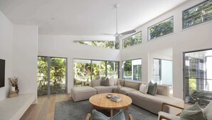 Ein modernes Wohnzimmer mit einem großen Ecksofa, einem runden Couchtisch und einem Deckenventilator.