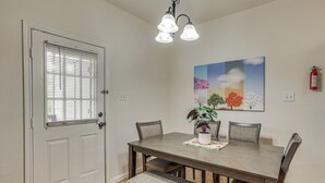 A dining area with a wooden table, cushioned chairs, a bench, a potted plant, and a painting on the wall. - Suburban San Antonio Stay Near Parks & Hospitals (San Antonio)