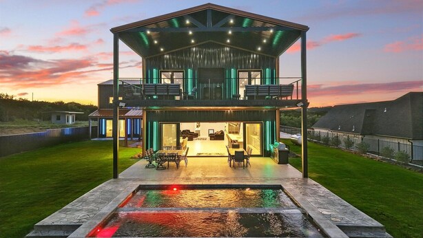 A modern two-story house with a covered outdoor patio and a swimming pool. - Lakefront resort home. Sleeps 26+! Boat dock, kayaks, pool, hot tub & more! (Graham)