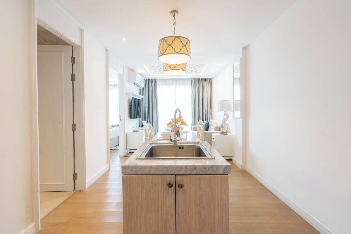 A modern kitchen with a central island, a built-in sink, and a pendant light.